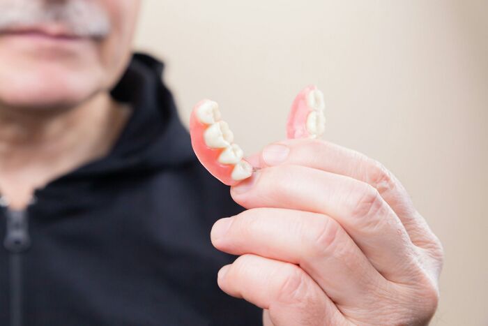 Close-up of a man holding unusual personal belongings, specifically a set of lost and found dentures.