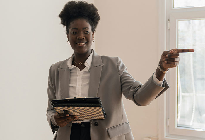 Woman in professional attire holding a tablet and pointing, illustrating disturbing things found in homes of seemingly normal people.