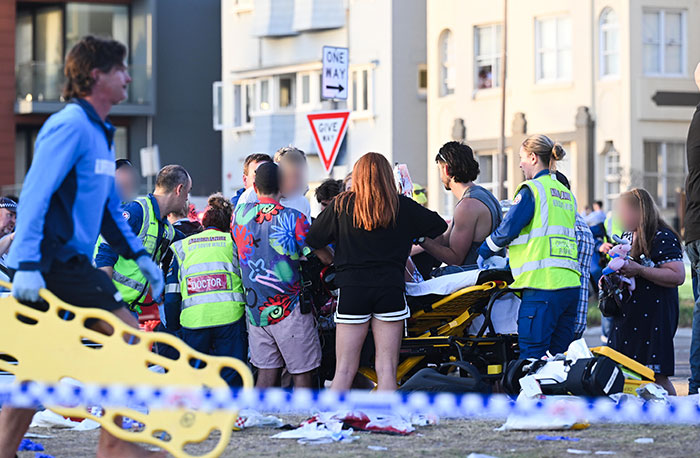 Emergency responders and bystanders assist during a Bondi Beach attack where a woman protects a 3-year-old girl.