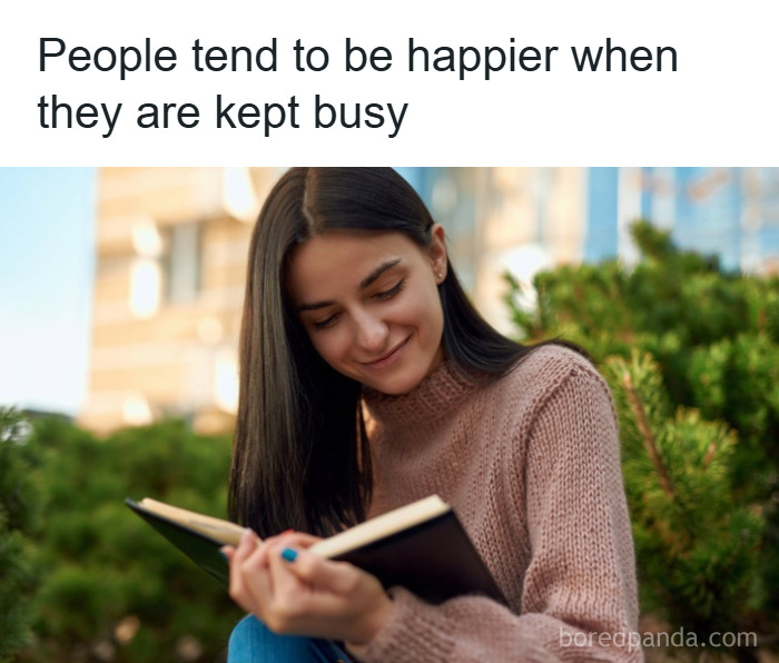 Young woman reading a book outdoors, illustrating psychology facts about happiness and staying busy in everyday life.