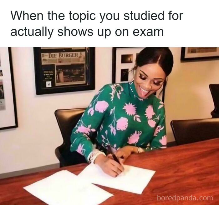 Student happily writing at a desk, illustrating college memes about students running on hope and energy drinks during exams.