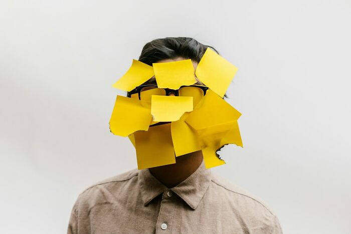 Person with glasses covered in yellow sticky notes, symbolizing people sharing historical facts unknown until recently.