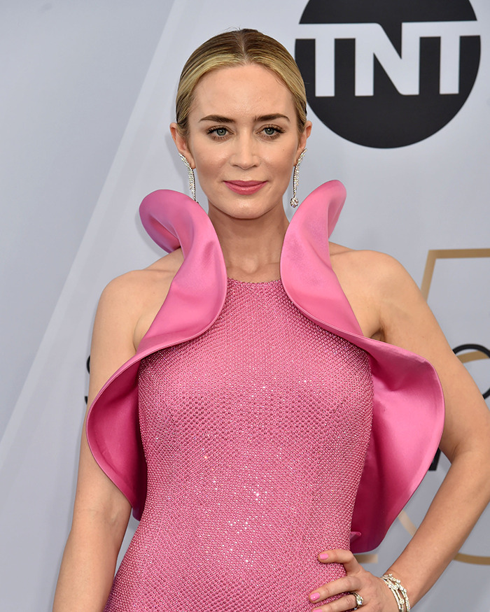 Emily Blunt in a pink textured dress with ruffled shoulders, attending an event amid plastic surgery rumors and surgeon debate. Emily Blunt in a pink textured dress with ruffled shoulders, attending an event amid plastic surgery rumors and surgeon debate.