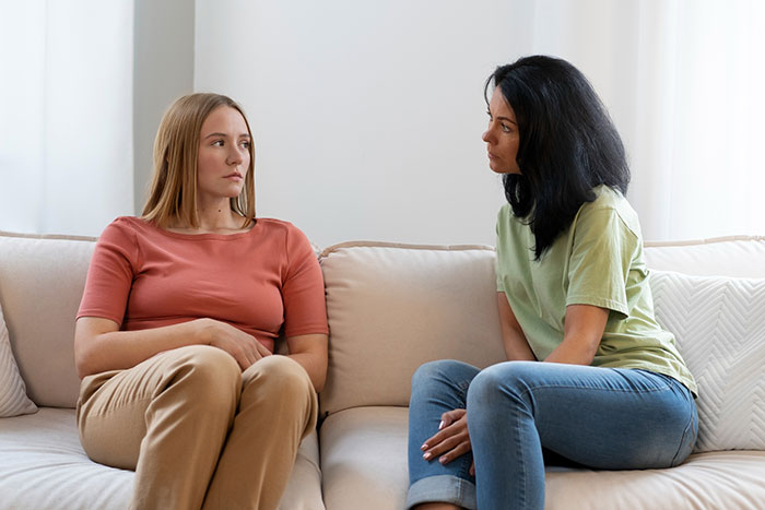 Two women sitting on a couch having a serious conversation about entitled mother expenses with son and girlfriend. Two women sitting on a couch having a serious conversation about entitled mother expenses with son and girlfriend.