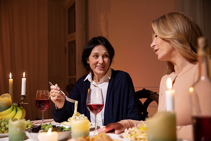 Two women having dinner and wine in a cozy setting, discussing entitled mother expenses with son and girlfriend. Two women having dinner and wine in a cozy setting, discussing entitled mother expenses with son and girlfriend.
