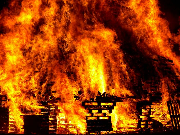 A large fire engulfing wooden pallets with intense flames testing your moral compass and shocking dilemmas.