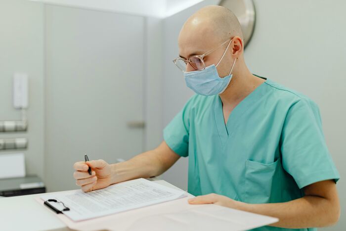Healthcare professional wearing scrubs and a mask, reviewing documents representing moral compass dilemmas and decision-making.