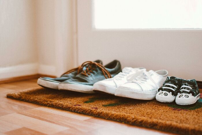 Three pairs of shoes, including adult and child sizes, neatly placed on a doormat testing your moral compass.