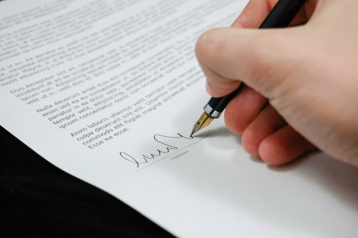 Close-up of a hand signing a document, representing your moral compass tested with challenging ethical dilemmas.