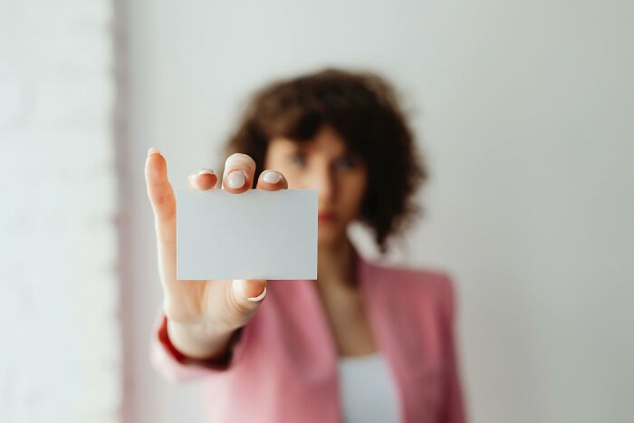 Woman in pink blazer holding a blank card forward, symbolizing a moral compass facing shocking dilemmas.