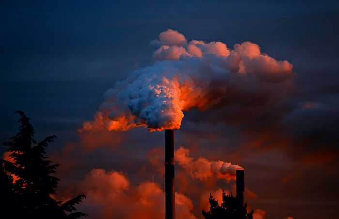 Smoke billows from factory chimneys against a dark sky, symbolizing moral dilemmas and testing your moral compass.