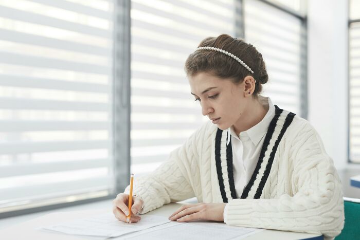 Young woman focused on writing at a desk, representing the challenge of testing your moral compass with dilemmas.