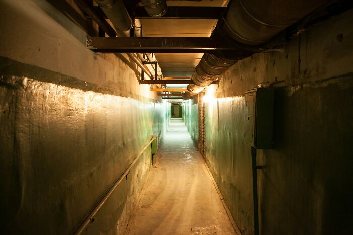 Dimly lit underground corridor with exposed pipes, illustrating people share historical facts unknown until recently.