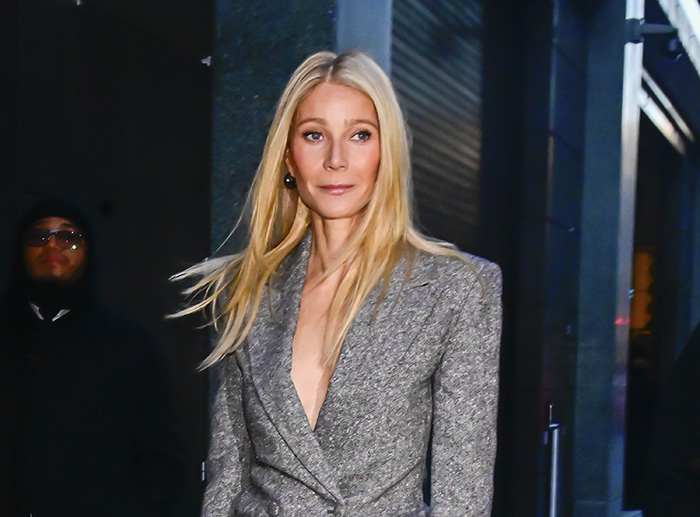 Gwyneth Paltrow in a gray blazer walking outdoors at night, involved in a controversy with an HR executive hypocrite.