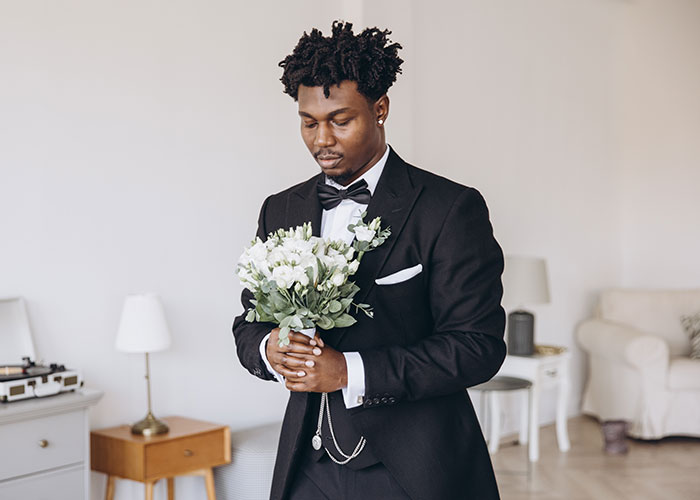 Man in tuxedo holding wedding bouquet, appearing thoughtful and waiting before wedding day without closure. Man in tuxedo holding wedding bouquet, appearing thoughtful and waiting before wedding day without closure.