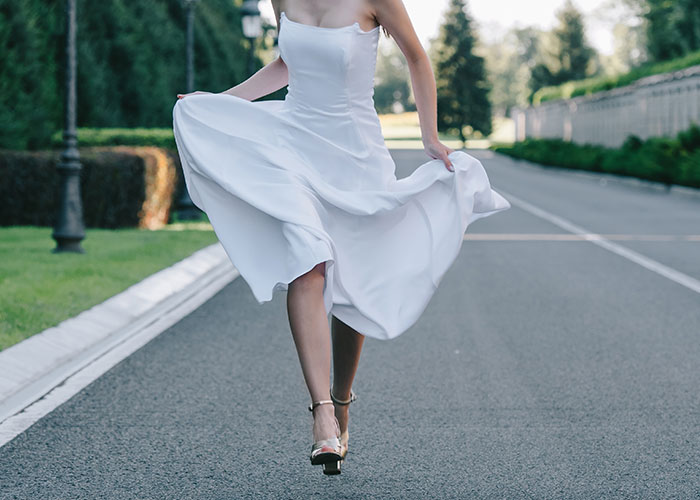 Bride in white dress running away on empty road symbolizing fiancé disappears before wedding and man left without closure. Bride in white dress running away on empty road symbolizing fiancé disappears before wedding and man left without closure.