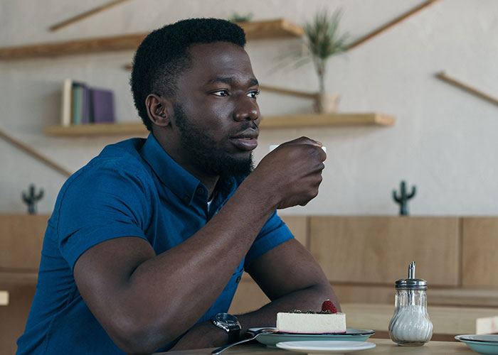 Man in blue shirt sitting thoughtfully at a table, symbolizing man left without closure after fiancé disappears before wedding. Man in blue shirt sitting thoughtfully at a table, symbolizing man left without closure after fiancé disappears before wedding.