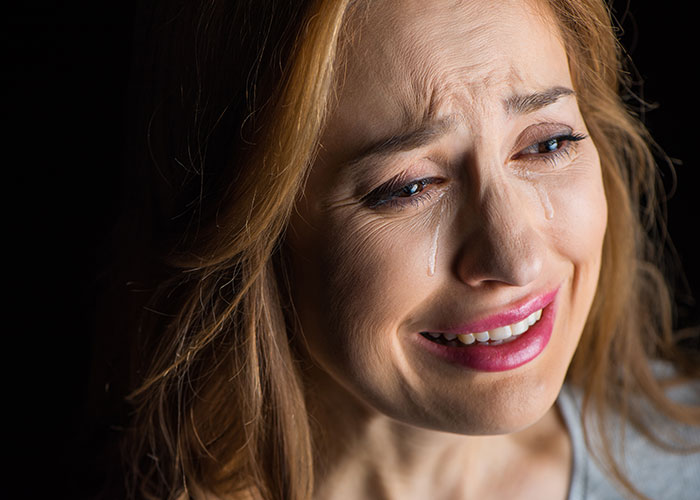 Woman crying with tears streaming down her face, expressing pain and sadness after fianc&eacute; disappears before wedding.