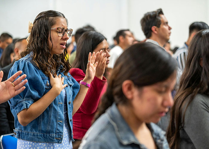 Young people with closed eyes and raised hands in a group setting sharing the moment they realized they are in a cult.