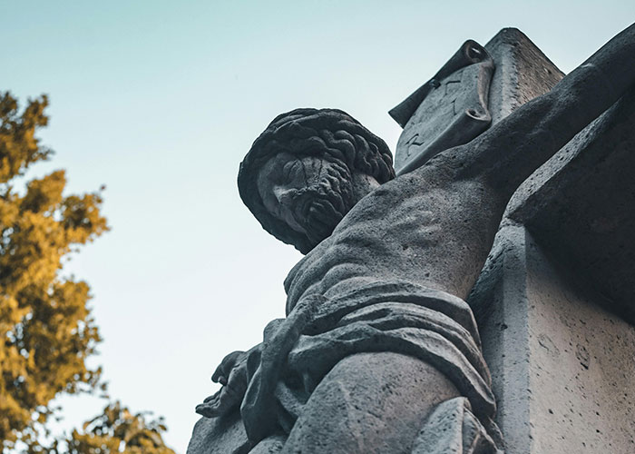 Stone statue of a man on a cross, depicting a moment related to people realizing they are actually in a cult.