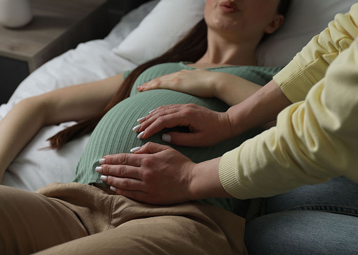 Hands resting on the pregnant belly of a woman, illustrating trust and support among former cult members.