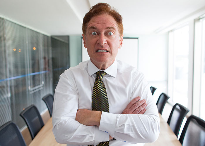 Man with anxious expression and crossed arms in a conference room representing former cult members' realization moment.