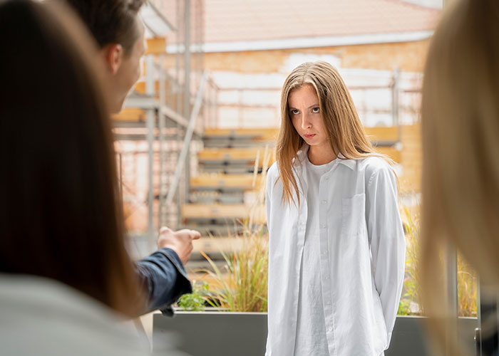 Young woman in a white shirt showing doubt and distress during a tense conversation about cult experiences and awareness.