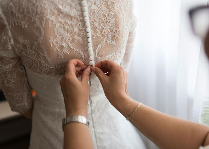 Hands buttoning lace dress on a woman, capturing the moment people share realizing they are actually in a cult.