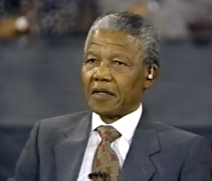 Elderly man in a suit and patterned tie speaking during an interview about true stories that sound made up.