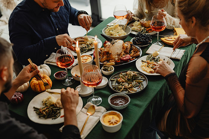 Family gathered around Thanksgiving dinner table with turkey and side dishes, capturing tense holiday emotions.