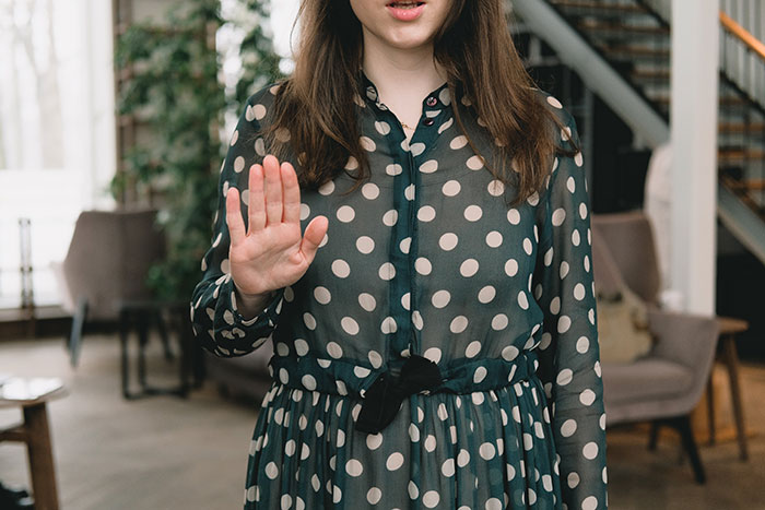 Woman in polka dot dress gesturing stop inside a house, symbolizing family tired of hosting ungrateful relatives for Christmas.