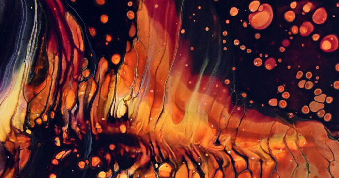 Abstract acrylic pour artwork showing vibrant chain pull pouring experiment with orange, black, and yellow fluid patterns.