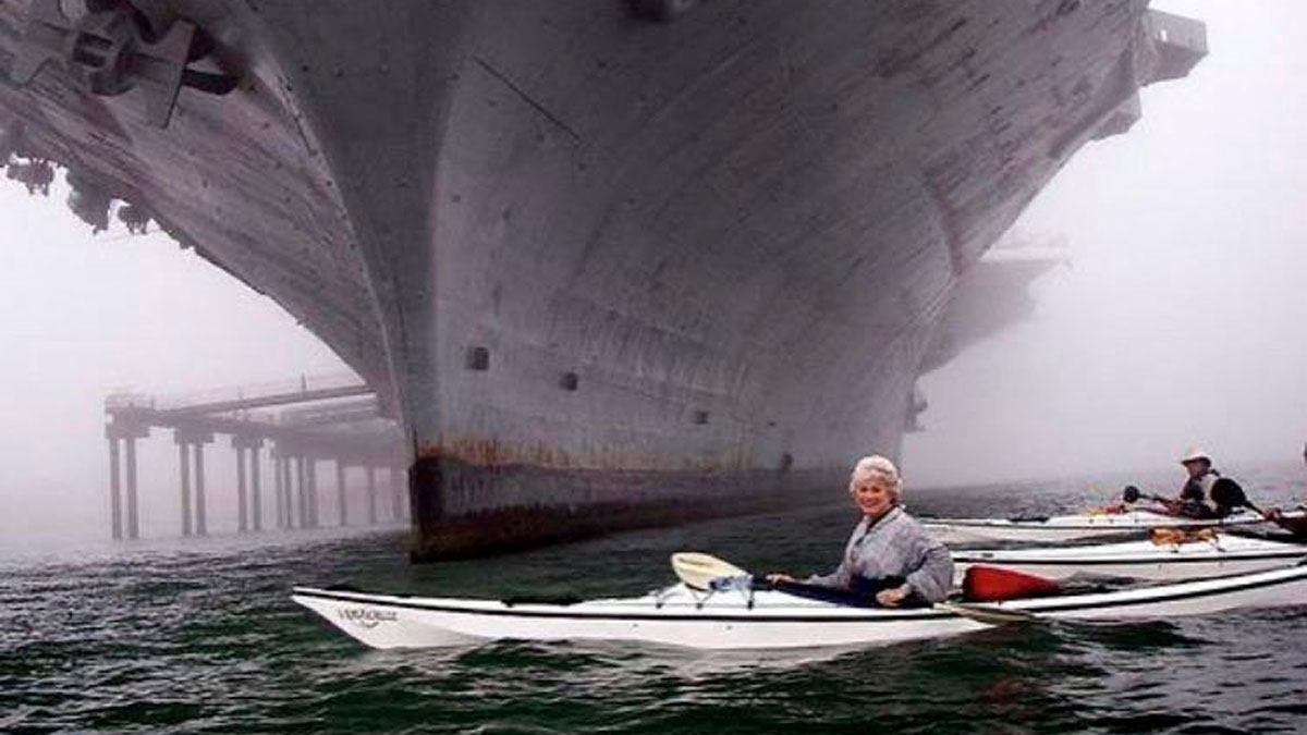 Kayakers paddling near the massive hull of a ship, creating a striking image for those with megalophobia.