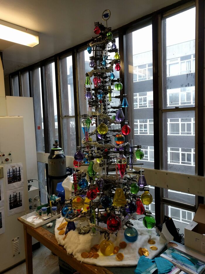 Creative workplace Christmas decoration featuring a colorful chemistry-themed tree with lab glassware ornaments.