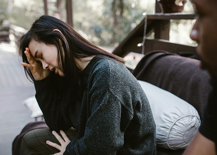 Woman looking distressed and deep in thought while sitting on a couch, related to fiancée’s unexpected request before wedding. Woman looking distressed and deep in thought while sitting on a couch, related to fiancée’s unexpected request before wedding.