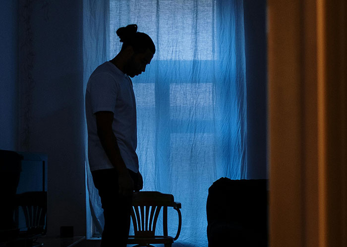 Man standing alone in a dimly lit room, appearing deep in thought about fiancée’s unexpected request before wedding. Man standing alone in a dimly lit room, appearing deep in thought about fiancée’s unexpected request before wedding.