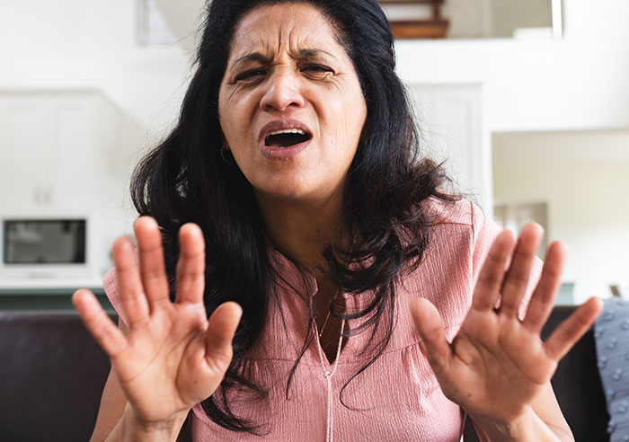 Woman showing distress and resistance while raising hands, representing a restraining order against mother-in-law after long marriage.