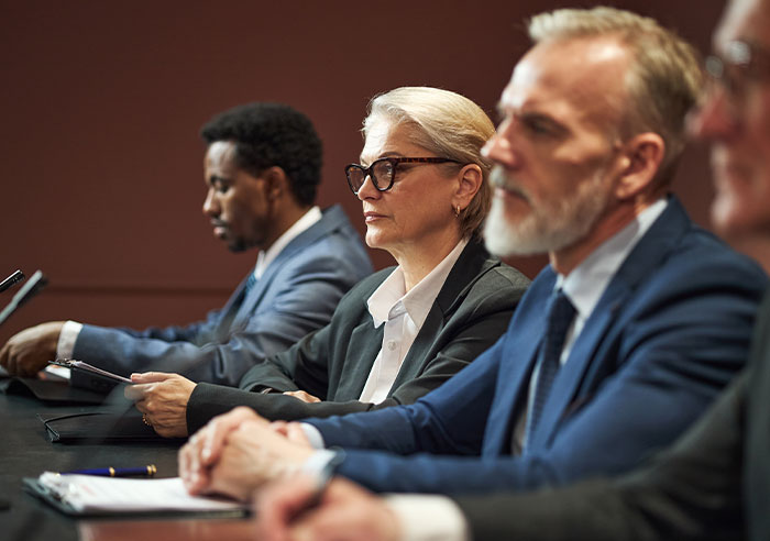 Woman in glasses sitting in legal hearing, representing restraining order case against mother-in-law after years of marriage.