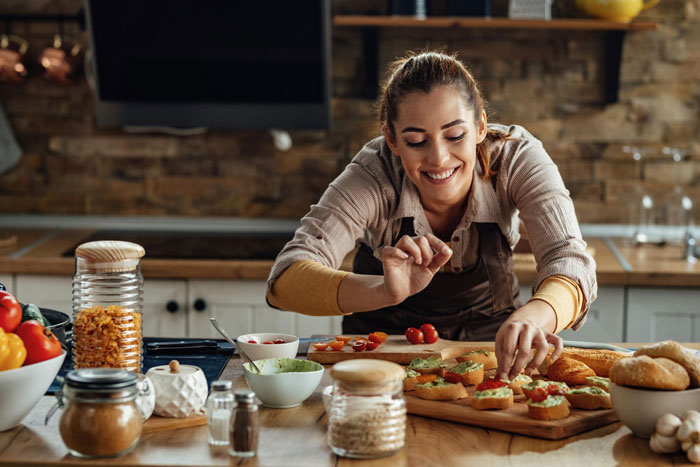 Woman sneaking veggies into meals in a rustic kitchen to protect teen’s health with a smile while preparing food. Woman sneaking veggies into meals in a rustic kitchen to protect teen’s health with a smile while preparing food.