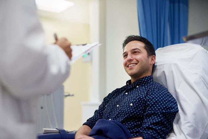 Smiling man in a hospital bed talking with a doctor after telling his family he doesn’t want a funeral. Smiling man in a hospital bed talking with a doctor after telling his family he doesn’t want a funeral.
