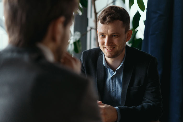 Man in a suit smiling during a conversation, illustrating a story about his hometown blowing up his phone after funeral wishes. Man in a suit smiling during a conversation, illustrating a story about his hometown blowing up his phone after funeral wishes.