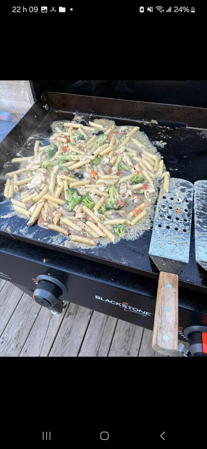 Pasta with mixed vegetables cooking unevenly on a Blackstone griddle, an example of food pics that deserve to be shamed online