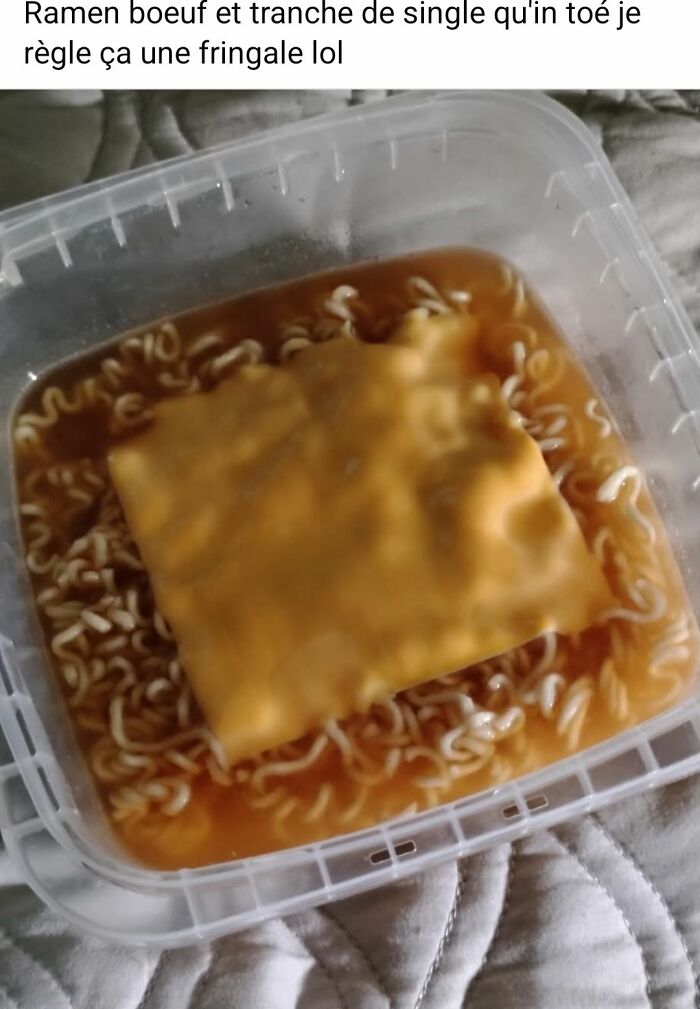 Ramen noodles in plastic container topped with a slice of processed cheese, an unusual food combination.