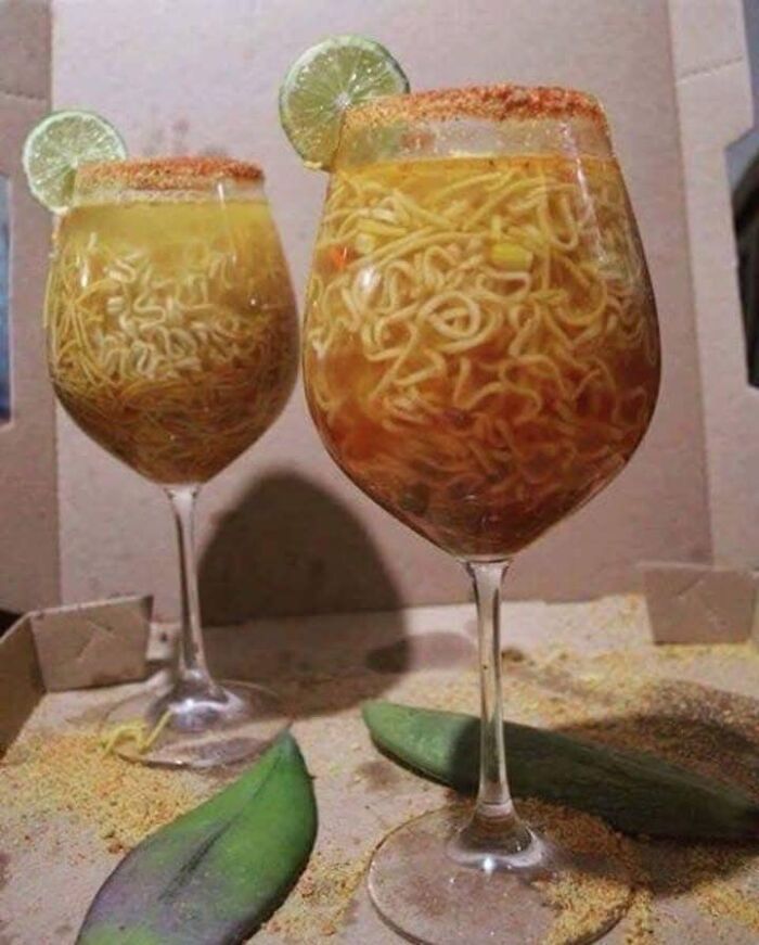 Two wine glasses filled with noodles and broth garnished with lime and spice, a bizarre food pic to be shamed online.