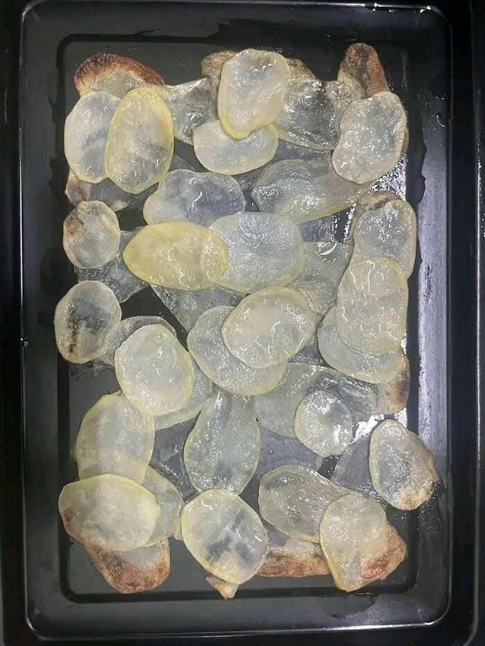 Undercooked and translucent homemade potato chips on a baking tray, a food pic that deserves to be shamed online.
