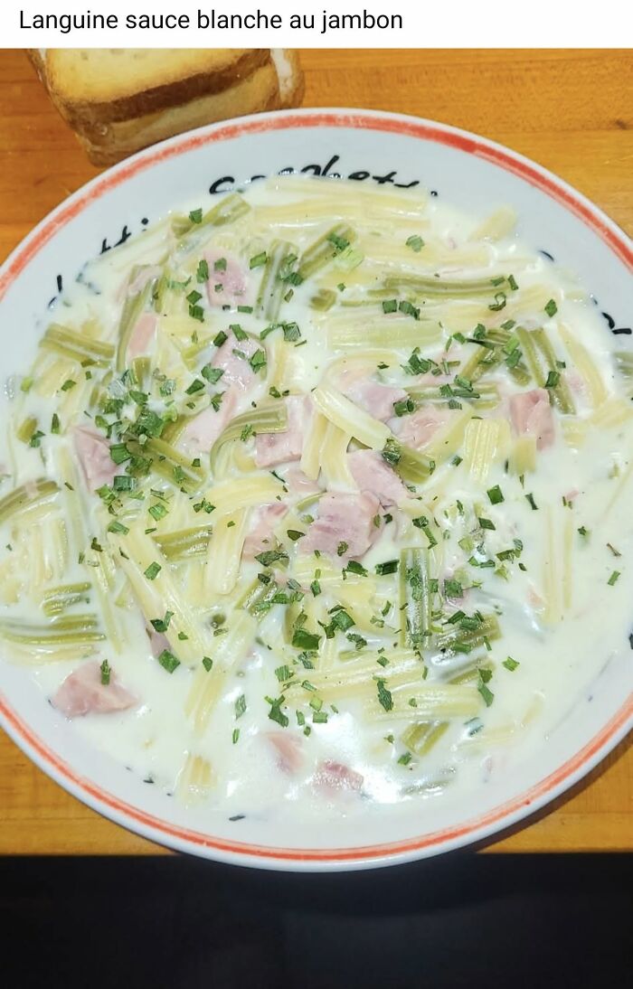 Bowl of creamy pasta with ham and herbs served with a slice of bread in a food pics that deserve to be shamed online collection.