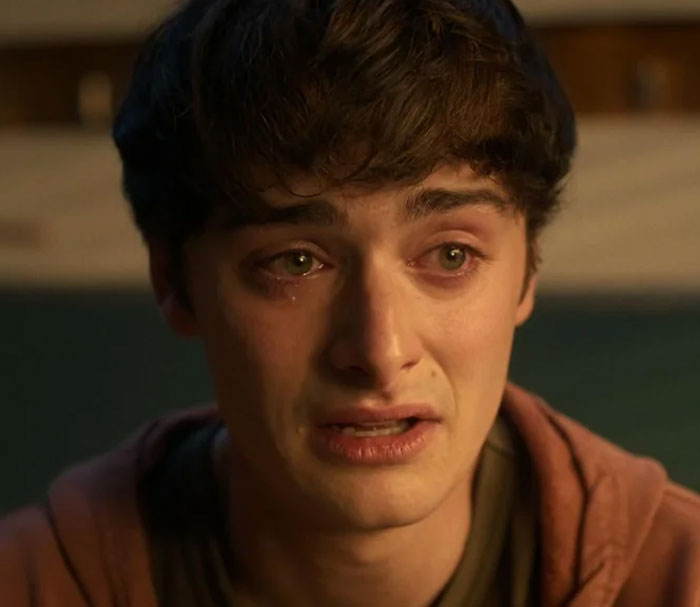 Young man crying emotionally in a dimly lit room captured from Stranger Things Season 5.