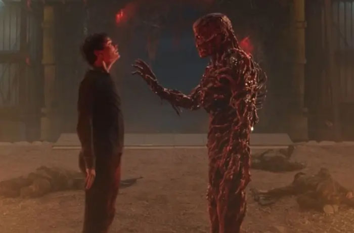 Scene from Stranger Things Season 5 showing a tense moment between a character and a monster in a dark, eerie setting.