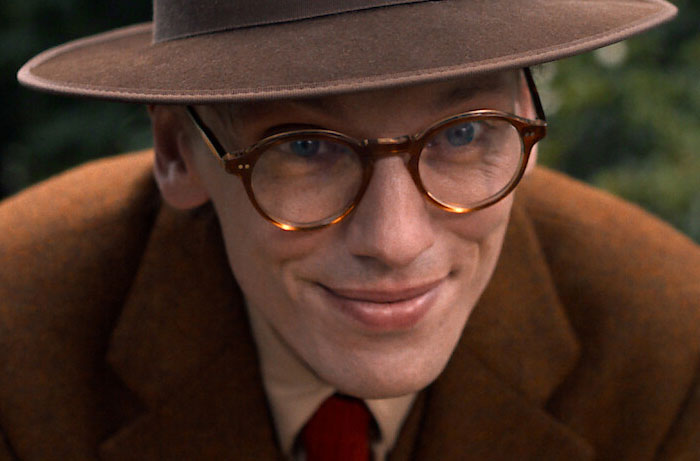 Close-up of a smiling man wearing glasses and a brown hat, related to Stranger Things Season 5 scenes.
