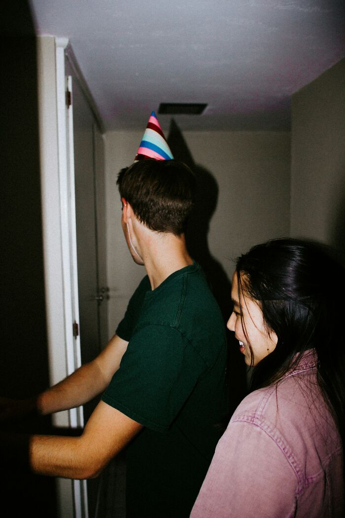Two friends at a party, one wearing a colorful hat, illustrating feelings of friendship and needing space.